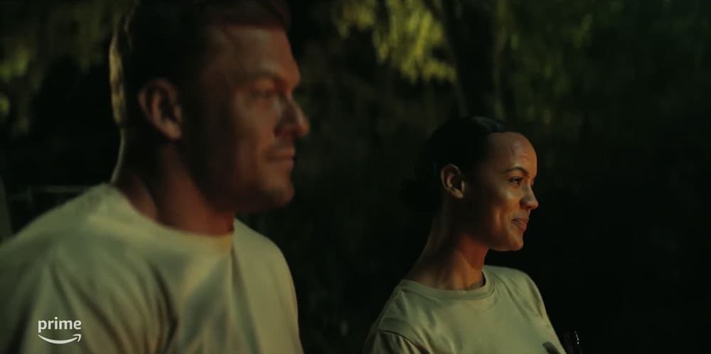 Alan Ritchson and Maria Sten share a beer around a campfire in 'Reacher'
