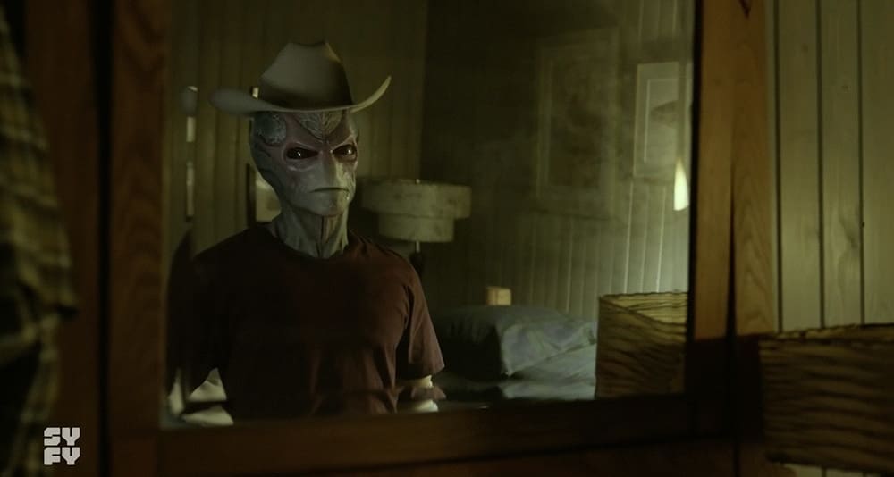 An alien (Alan Tudyk) looks at himself in a mirror, from 'Resident Alien'.